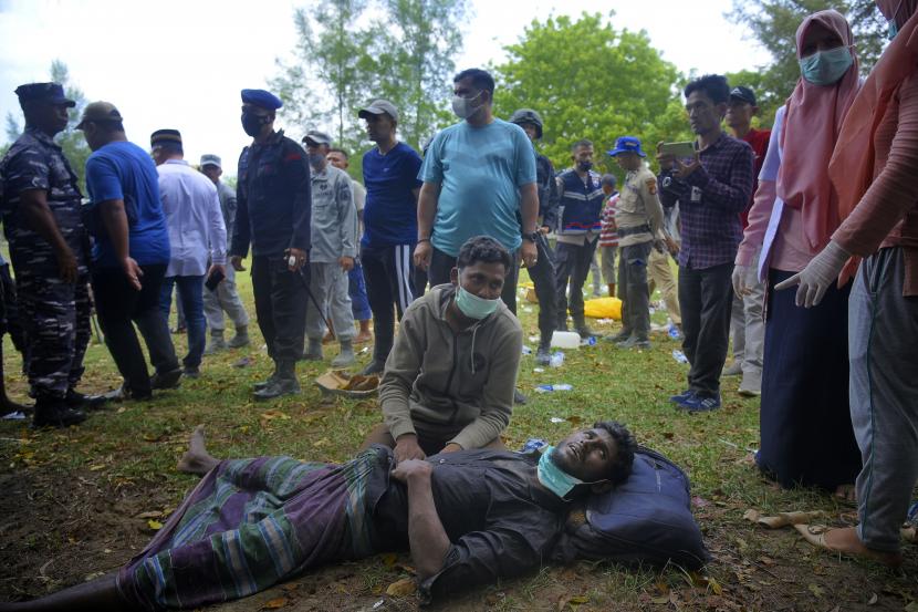Seorang pria etnis Rohingya terbaring di tanah saat menunggu perawatan medis setelah mendarat di pantai Indra Patra di desa Ladong, provinsi Aceh, Indonesia, Ahad, 25 Desember 2022. 
