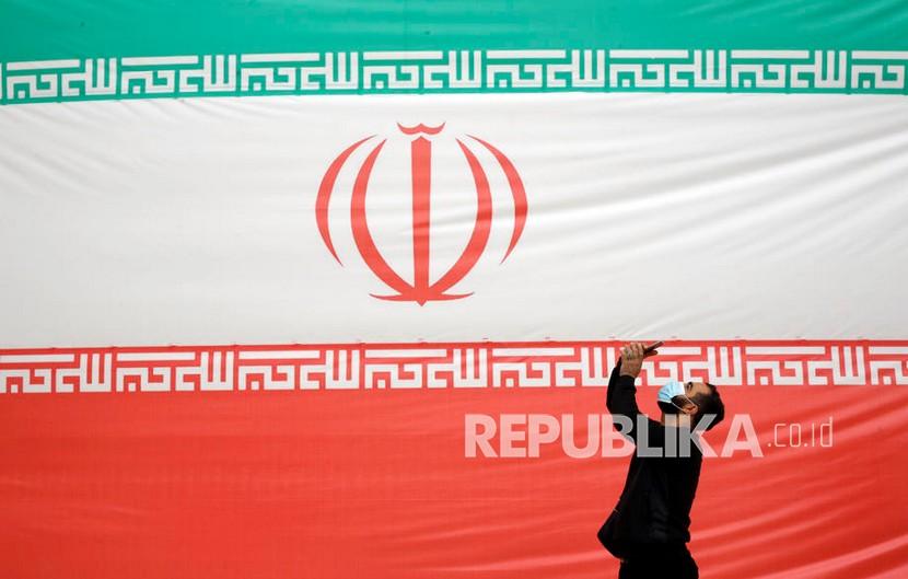  Seorang pria berfoto di depan bendera besar Iran alun-alun Azadi, Teheran, Iran, 11 Februari 2022.