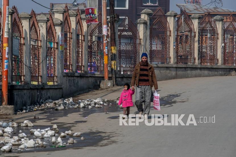  Seorang pria Kashmir berjalan dengan anaknya saat mogok untuk memperingati kematian pemimpin separatis Maqbool Bhat di Srinagar, Kashmir yang dikendalikan India, Kamis (11/2).