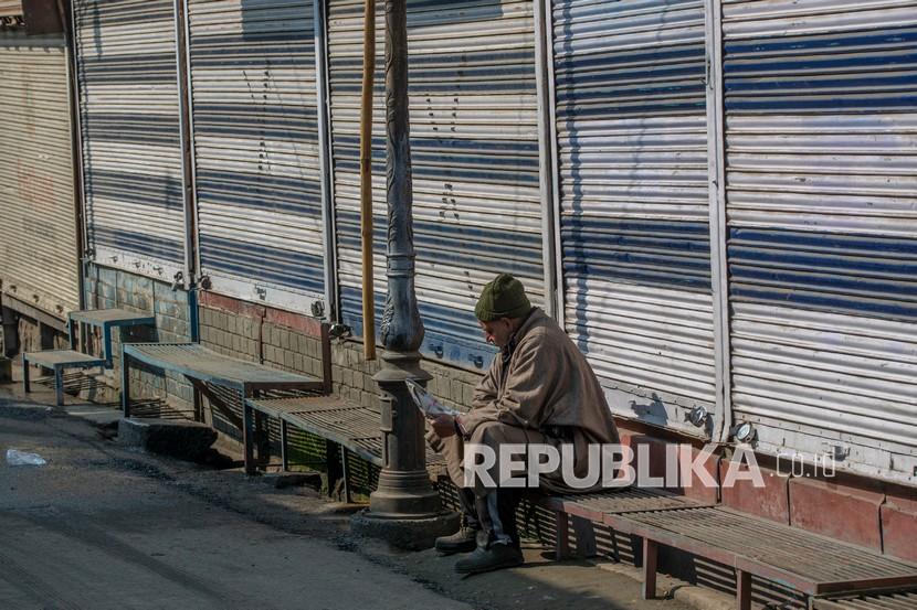India Kecam Ahli PBB Atas Kekhawatiran tentang Kashmir. Seorang pria Kashmir membaca koran saat dia duduk di luar pasar tertutup selama pemogokan untuk menandai peringatan kematian pemimpin separatis Maqbool Bhat di Srinagar, Kashmir yang dikendalikan India, Kamis (11/2).
