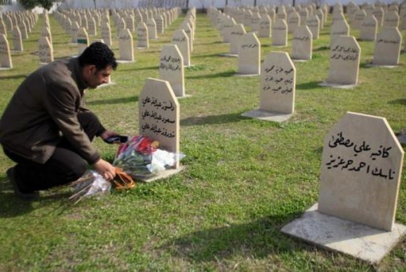Seorang pria meletakkan bunga di salah satu makam korban serangan gas beracun di Halabja, Irak pada 16 Maret 1988.