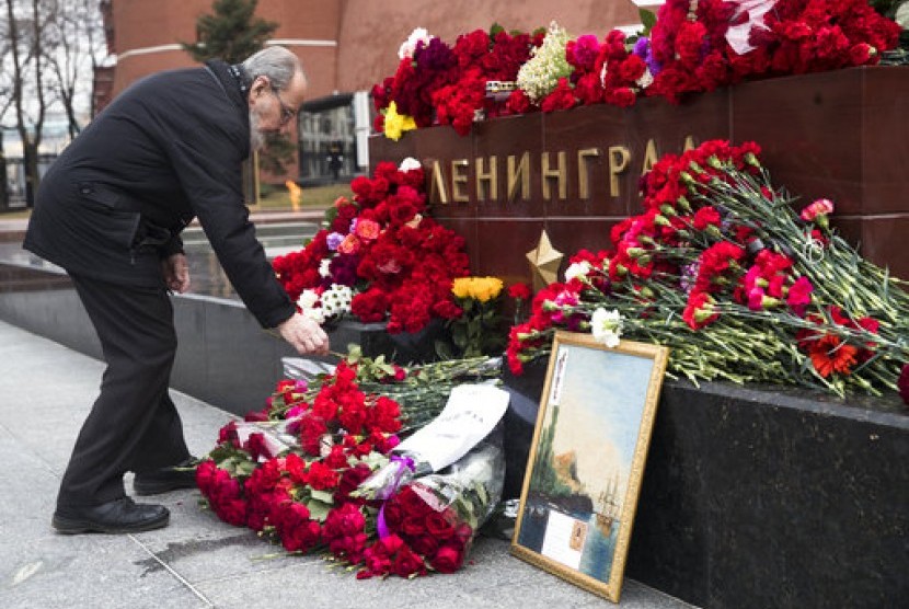 Seorang pria meletakkan bunga mengenang korban ledakan kereta bawah tanah St Petersburg di depan dinding Kremlin di Moskow, Rusia, Selasa (4/4).