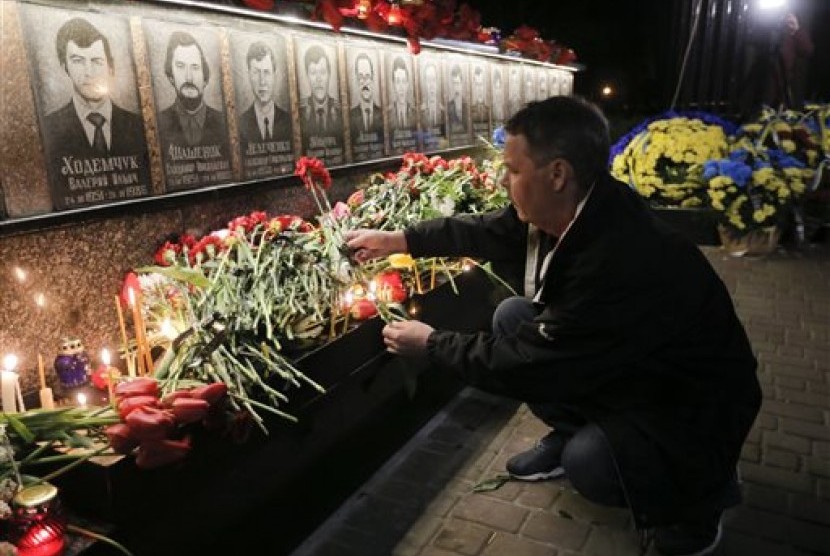 Seorang pria meletakkan bunga untuk menghormati korban bencana nuklir Chernobyl di tugu peringatan untuk pekerja fasilitas nuklir tersebut dan pemadam kebakaran yang gugur di Kota Slavutych, Ukraina, Selasa, 26 April 2016.
