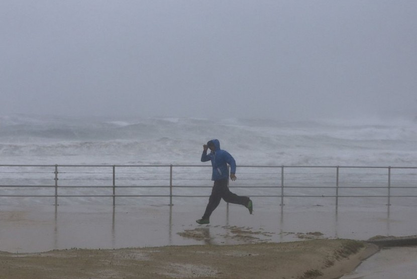 Seorang pria melewati Pantai Bondi, Sydney yang sedang pasang
