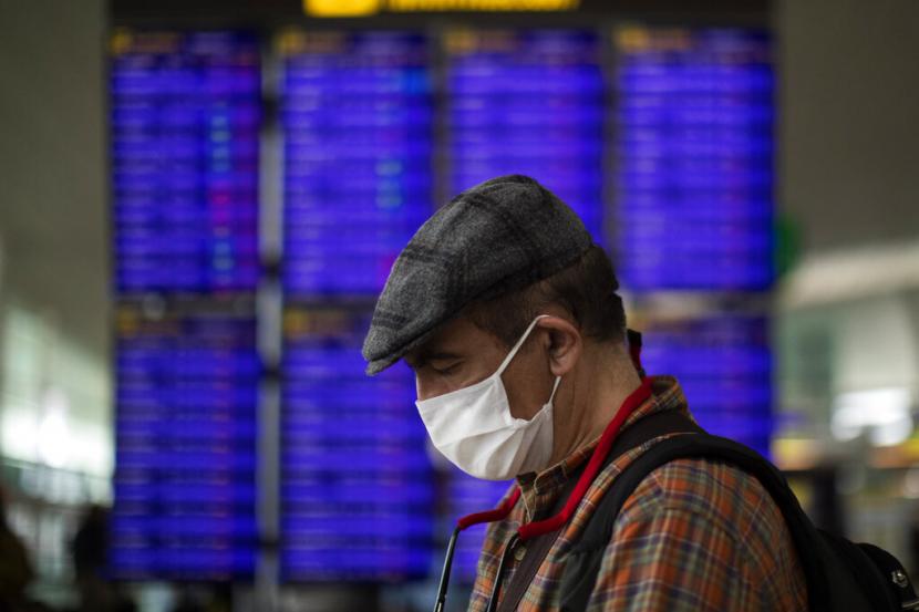 Seorang pria melihat ponselnya di depan papan informasi penerbangan di Bandara Barcelona, Spanyol, Kamis (12/3). Spanyol memberlakukan lockdown atau penutupan selama 15 hari.