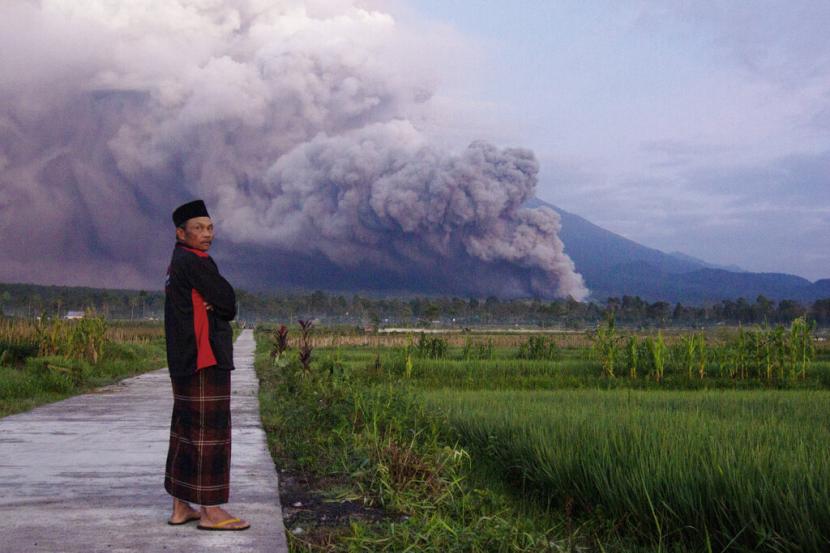 Seorang pria melihat saat Gunung Semeru mengeluarkan material vulkanik saat meletus pada Ahad, 4 Desember 2022 di Lumajang, Jawa Timur, Indonesia. Gunung berapi tertinggi di Indonesia di pulau Jawa yang paling padat penduduknya meletus pada hari Ahad.