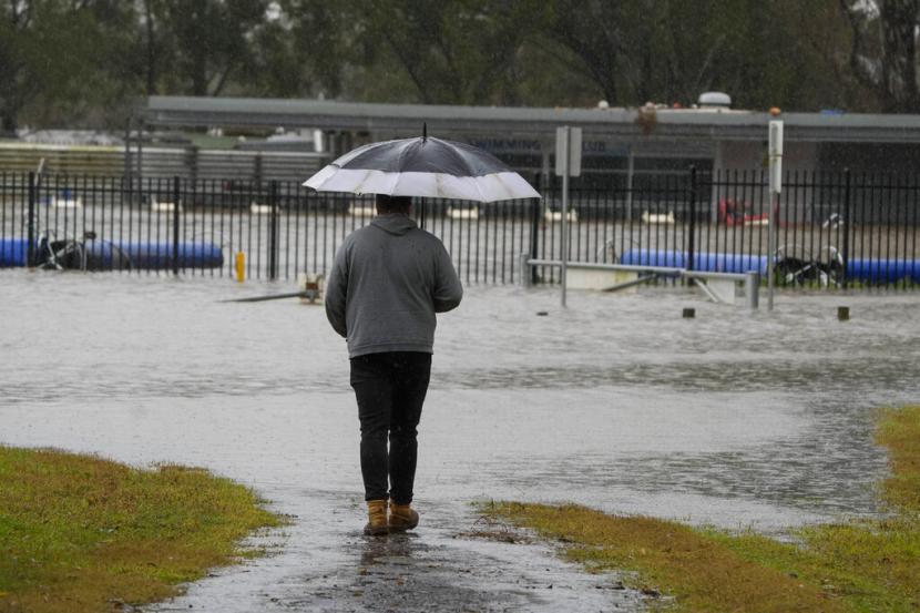 Seorang pria melihat tempat olahraga yang terendam banjir di Camden di pinggiran Sydney, Australia, Senin, 4 Juli 2022. Lebih dari 30.000 penduduk Sydney dan sekitarnya telah diperintahkan untuk mengungsi atau bersiap untuk meninggalkan rumah mereka pada hari Senin sebagai yang terbesar di Australia kota bersiap menghadapi banjir terburuk dalam 18 bulan.