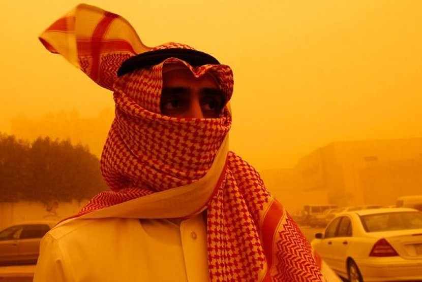 Seorang pria melindungi wajahnya dari terpaan panas gurun