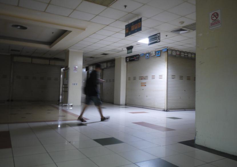 Seorang pria melintas di lorong pertokoan yang tutup di pusat servis dan toko komputer Harcomas Mangga Dua, Jakarta, Sabtu (2/5/2020). Sebagian besar pertokoan menutup usahanya sesuai surat edaran pemerintah untuk mengantisipasi penyebaran virus corona atau COVID-19.