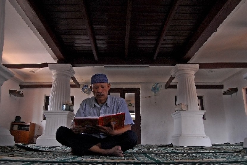 Seorang pria membaca Alquran usai shalat Dzuhur (ilustrasi).