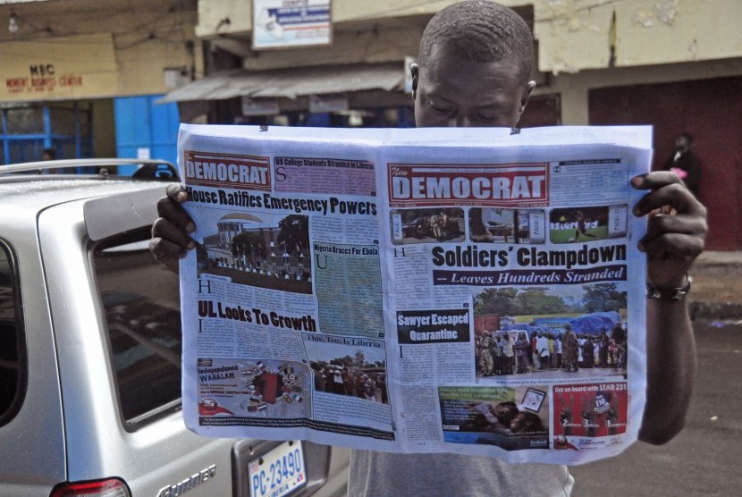 Seorang pria membaca suratkabar yang halaman depannya memuat mengenai wabah ebola di Monrovia, Liberia, Jumat (8/8) 