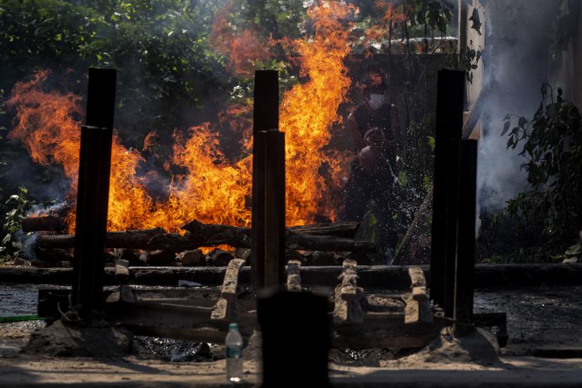 Seorang pria membersihkan tempat kremasi untuk membakar jenazah orang yang meninggal karena COVID-19 di Gauhati, India, Selasa, 27 April 2021. Kasus virus corona di India melonjak lebih cepat daripada di tempat lain di dunia.
