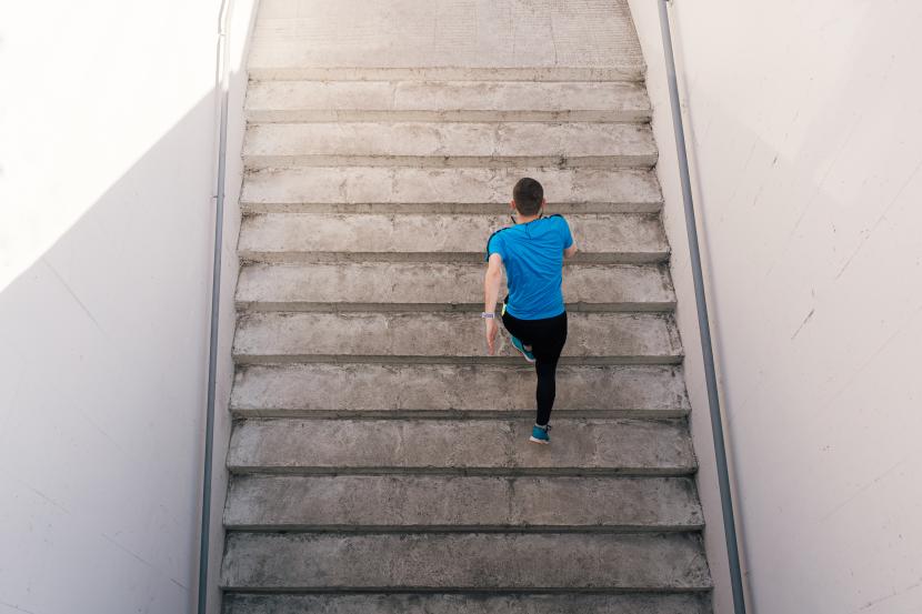 Seorang pria menaiki tangga (ilustrasi). Peneliti menyatakan aktivitas naik turun tangga lebih sehat dibandingkan jalan kaki 10 ribu langkah.