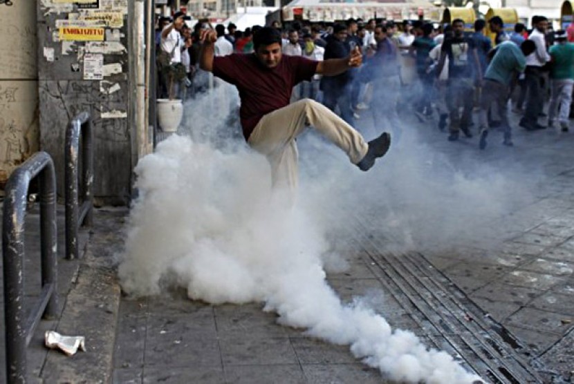 Seorang pria mencoba menendang kaleng gas air mata, saat demo memrotes film anti-Islam berlangsung di Yunani, Ahad (23/9) waktu setempat.