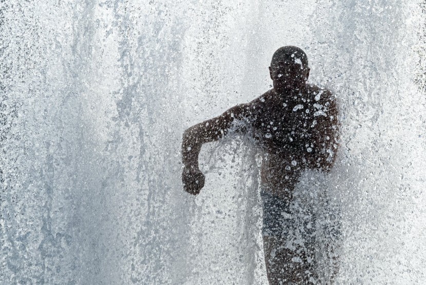 Seorang pria mendinginkan diri di tengah cuaca panas ekstrem Eropa di air mancur taman Lustgartendi Berlin, Jerman, Rabu (26/6).