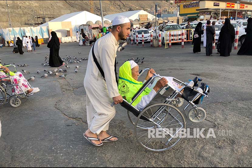 Seorang pria mendorong kursi roda ibunya menuju Masjid Al Haram, Mekkah, Kamis (24/5) waktu setempat.