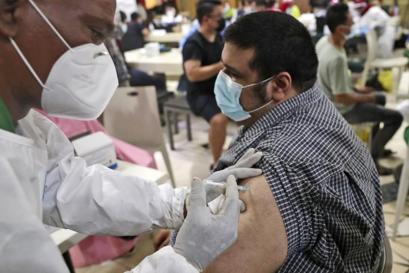  Seorang pria menerima suntikan vaksin COVID-19 saat vaksinasi massal untuk pedagang dan pekerja di Pasar Tanah Abang di Jakarta, Indonesia, Rabu, 17 Februari 2021