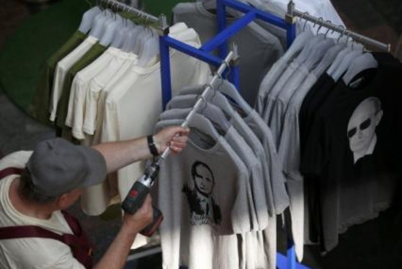 Seorang pria mengamati rak pakaian di sebuah toko busana.