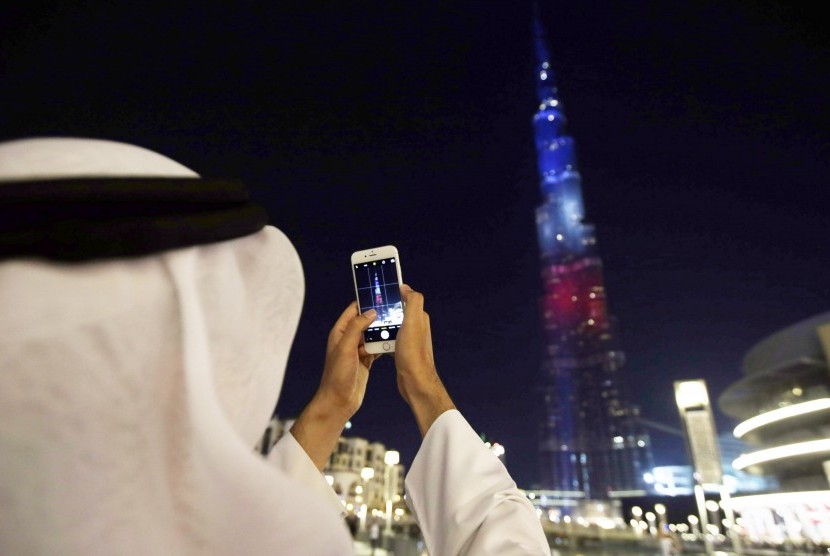Masjid Dibuka Lagi, Burj Khalifa Gelar Pertunjukan Lampu. Seorang pria mengambil foto bangunan ikonik Dubai Burj Khalifa.