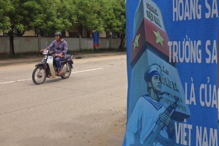 Seorang pria mengendarai sepeda motor melewati poster yang menegaskan kedaulatan Vietnam di Laut Cina Selatan di Pulau Phu Quoc pada 11 September 2014.