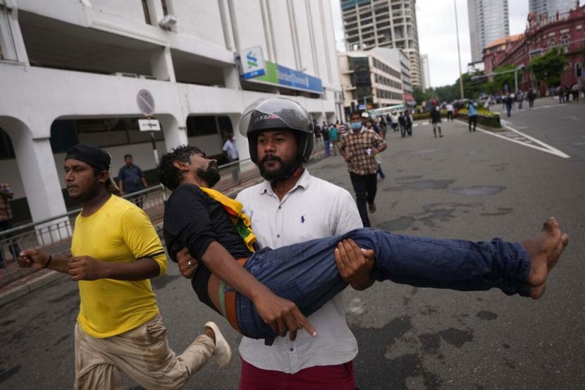 Seorang pria menggendong seorang pengunjuk rasa yang terluka dalam bentrokan antara polisi dan pengunjuk rasa anti pemerintah di Kolombo, Sri Lanka, Kamis, 9 Juni 2022. Militer Sri Lanka terpaksa melepaskan tembakan untuk menahan kerusuhan di sebuah pom bensin di Visuvamadu pada Ahad (19/6/2022) waktu setempat.