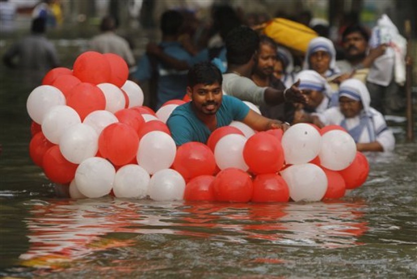 Seorang pria menggunakan balon agar mengapung saat melalui banjir di Chennai, Tamil Nadu, India, Kamis, 3 Desember 2015. Hujan terderas dalam 100 tahun terakhir di Chennai telah menyebabkan banjir.