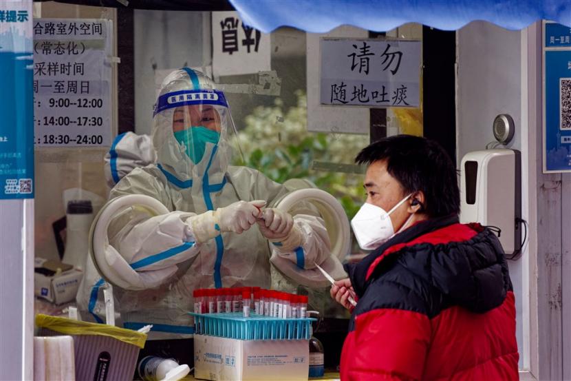  Seorang pria menjalani tes PCR Coronavirus di bilik pengujian jalanan, di Shanghai, China, 14 Desember 2022. China tidak akan lagi melaporkan kasus Covid-19 tanpa gejala dalam laporan hariannya, menurut pengumuman Komisi Kesehatan Nasional pada 14 Desember. Dengan pelonggaran pembatasan Covid-19, peningkatan jumlah infeksi beredar di Shanghai. Tahun ini musim liburan dihiasi dengan orang-orang yang tinggal di rumah pulih dari virus. Pusat perbelanjaan dan restoran sebagian besar kosong, sementara orang terlihat di jalanan pada pagi hari sebelum dan sore hari setelah bekerja. 