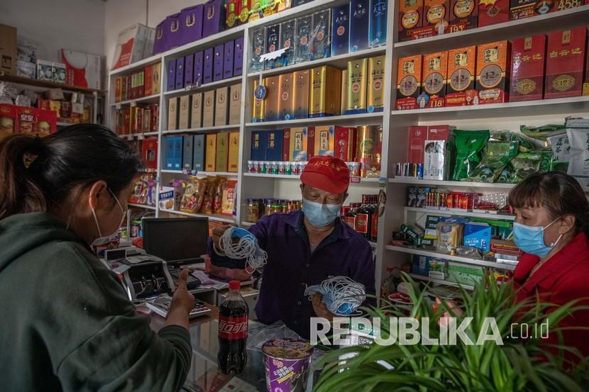 Seorang pria menjual masker kepada seorang wanita di sebuah toko di wilayah pedesaan Wuhan, Cina, Selasa (14/4). Sebagian besar penduduk desa di daerah pedesaan Wuhan kembali bekerja di ladang setelah dicabutnya lockdown. Pada 26 April 2020 jumlah pasien corona di rumah sakit Wuhan mencapai nol. Ilustrasi.