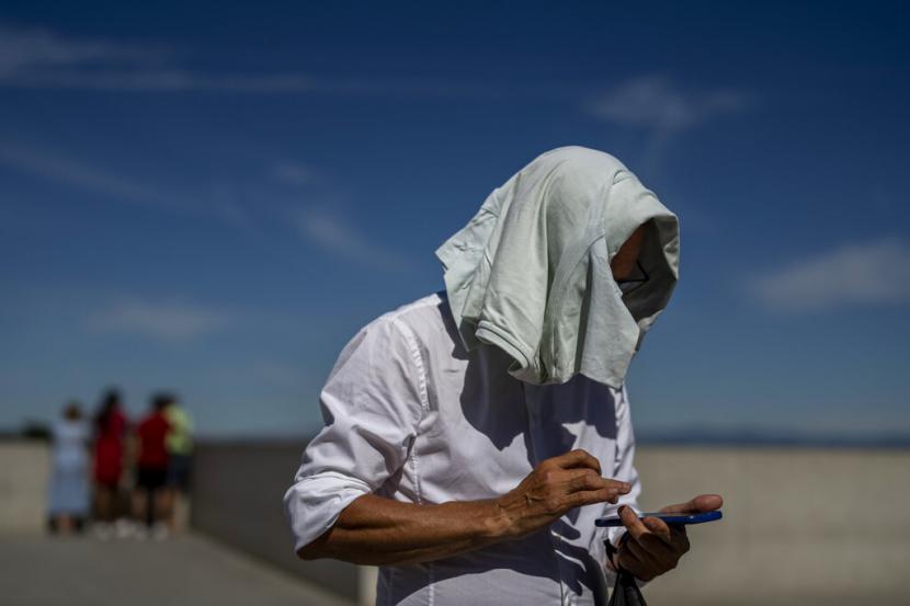 Seorang pria menutupi kepalanya dari matahari pada hari yang panas di Madrid, Spanyol, Jumat, 10 Juni 2022. Suhu meningkat dengan prediksi akan mencapai lebih dari 40 derajat Celcius (104 derajat Fahrenheit) pada akhir pekan di beberapa bagian Spanyol .
