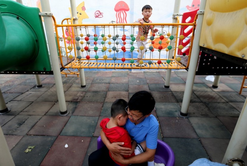 Seorang pria merawat anak dengan autisme di Beijing, Cina. Gangguan autisme lebih banyak ditemukan pada anak laki-laki daripada perempuan.