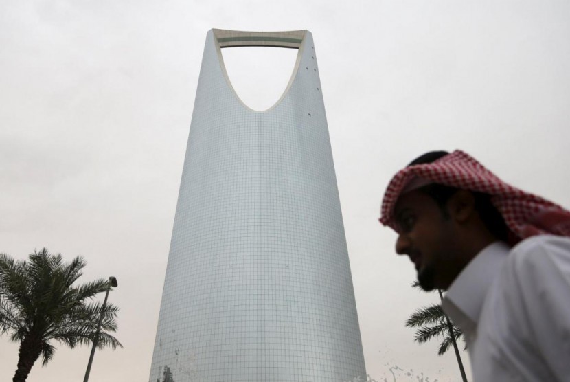 Seorang pria Saudi berjalan melewati Kingdom Centre Towerdi Riyadh, Arab Saudi.