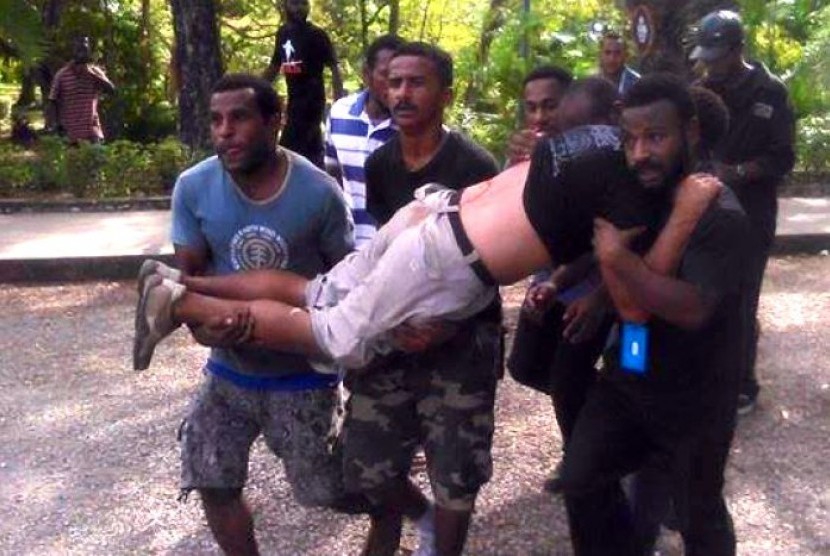Seorang pria yang dilaporkan ditembak polisi saat demonstrasi mahasiswa di Port Moresby, Papua Nugini digotong rekannya.