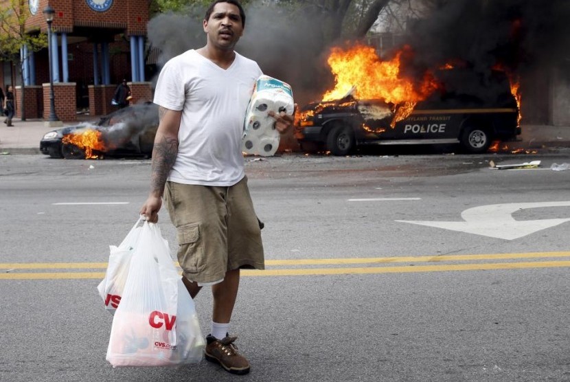 Seorang pria yang menjarah barang dalam kerusuhan di Baltimore, Maryland, AS, Senin (27/4)