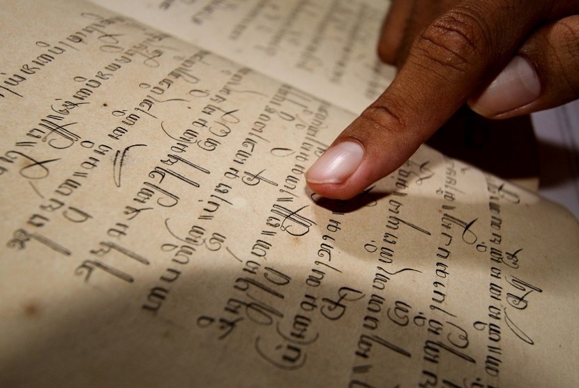 seorang pustakawan melakukan penyalinan naskah kuno berjudul 