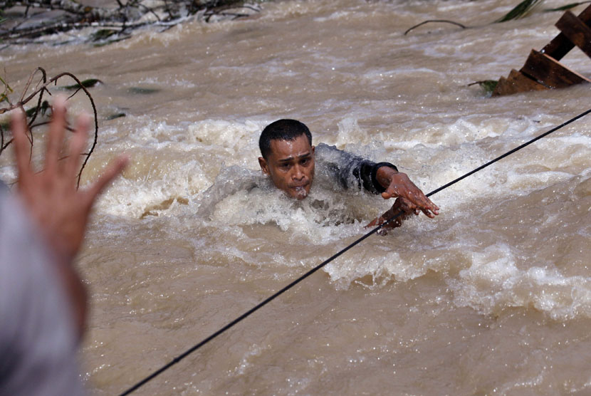 Seorang regu penyelamat menyeberangi sungai saat mencari korban tanah longsor akibat gempa di Serempah, provinsi Aceh, Indonesia, Jumat (5/7).  (AP/Binsar Bakkara)