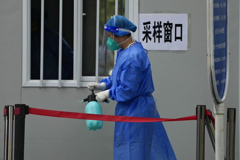 Seorang relawan dengan alat pelindung diri menyemprotkan disinfektan di sekitar lokasi pengujian COVID-19 di Beijing