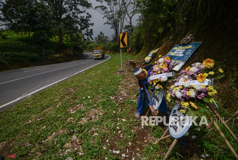 Seorang relawan membenahi karangan bunga duka cita di tempat kejadian perkara terbaliknya bus di Tanjakan Emen, Kabupaten Subang, Jawa Barat, Selasa (27/2). 