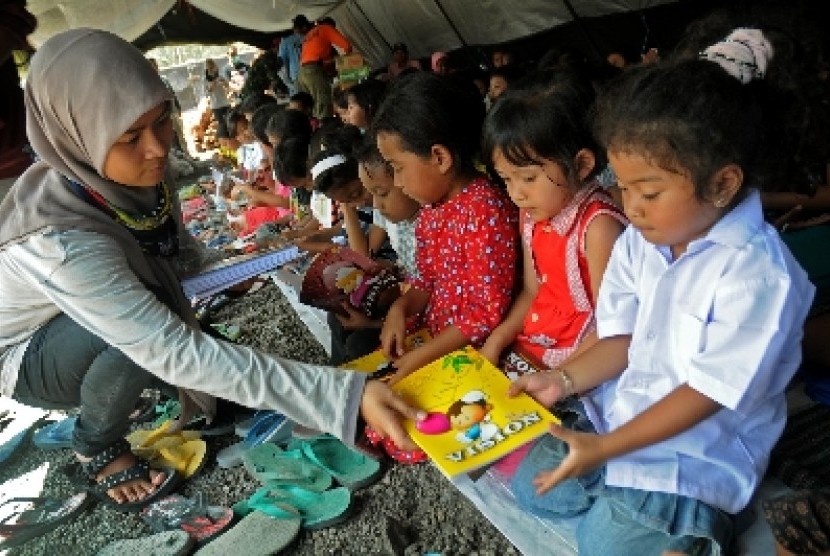 Seorang relawan menghibur anak-anak pengungsi korban dampak erupsi Gunung Kelud, di Dusun Laharpang, Kediri, Jawa Timur.