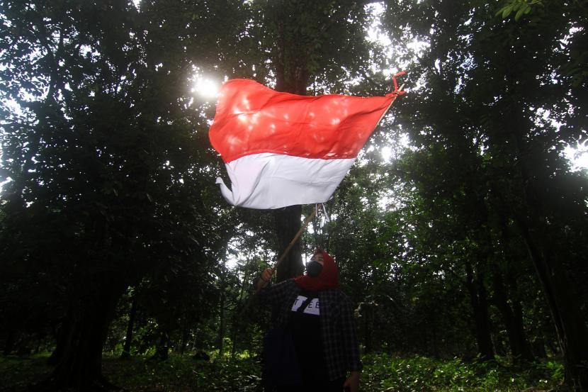 Seorang remaja mengibarkan bendera usai mengikuti upacara pengibaran bendera Merah Putih. 