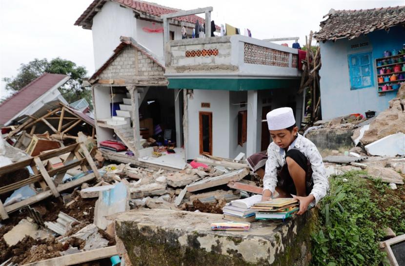  Seorang santri memegang buku di depan pesantrennya yang roboh akibat gempa bermagnitudo 5,6, di Cianjur, Rabu (23/11/2022). Menteri PUPR siap membangun rumah tahan gempa untuk korban di Cianjur, Jabar.
