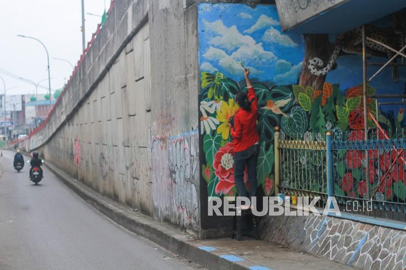 Seorang seniman menyelesaikan pembuatan mural di dinding bawah Flyover Arif Rahman Hakim, Depok, Jawa Barat, Selasa (28/12/2021). Kegiatan tersebut sebagai salah satu program penataan wajah kumuh di kawasan kolong flyover Arif Rahman Hakim yang rencananya akan dipergunakan sebagai taman dan sarana olahraga. 