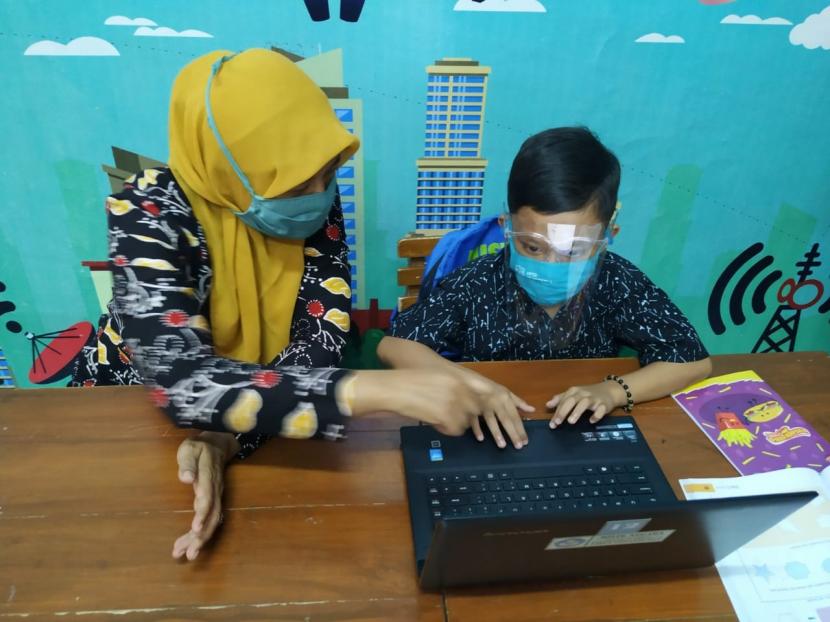 Seorang siswa kelas IV SDN 1 Kota Banjar, Jawa Barat, dipandu wali kelasnya untuk melakukan proses kegiatan belajar mengajar (KBM) secara daring di sekolahnya, Kamis (30/7). Siswa tersebut belajar di sekolah lantaran keluarganya tak memiliki gawai untuk digunakan dalam KBM secara daring.