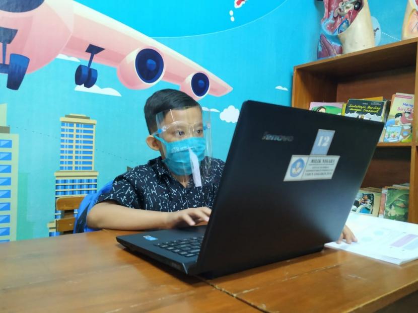 Seorang siswa kelas IV SDN 1 Kota Banjar, Jawa Barat, dipandu wali kelasnya untuk melakukan proses kegiatan belajar mengajar (KBM) secara daring di sekolahnya, Kamis (30/7). Siswa tersebut belajar di sekolah lantaran keluarganya tak memiliki gawai untuk digunakan dalam KBM secara daring. 