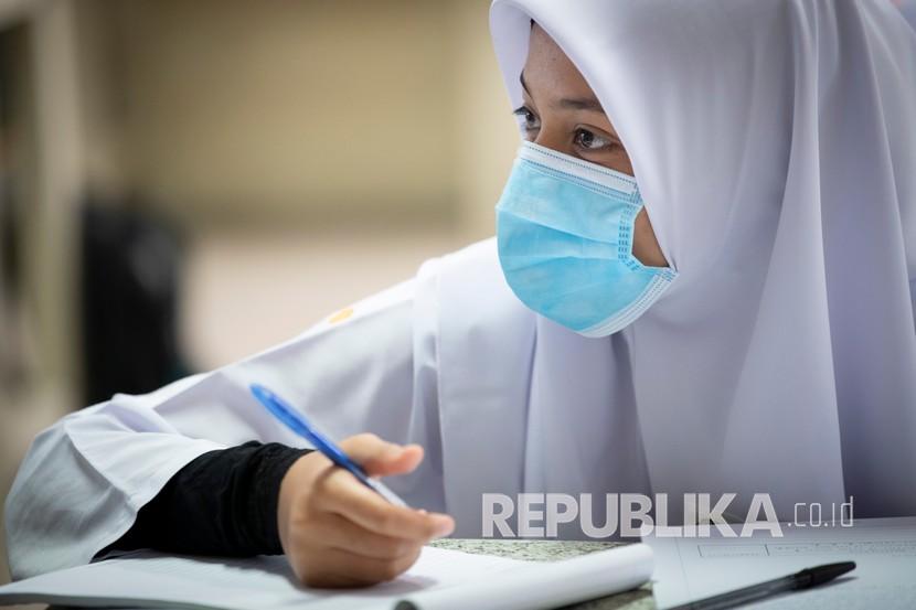 Seorang siswa mengenakan masker di ruang kelas selama hari pertama sekolah dibuka kembali di sebuah sekolah menengah di Putrajaya, Malaysia.