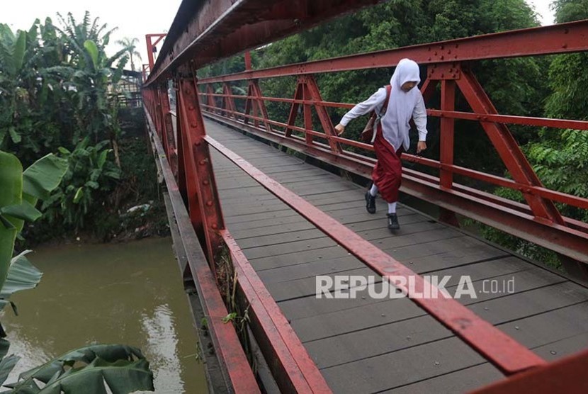 Seorang siswa SD berlari di jembatan saat akan ke sekolah untuk mengikuti Ujian Nasional (UN) di Desa Klambir V, Deli Serdang, Sumatera Utara, Senin (15/5). Ujian Nasional tingkat SD dilaksanakan secara serentak pada 15 - 17 Mei 2017.