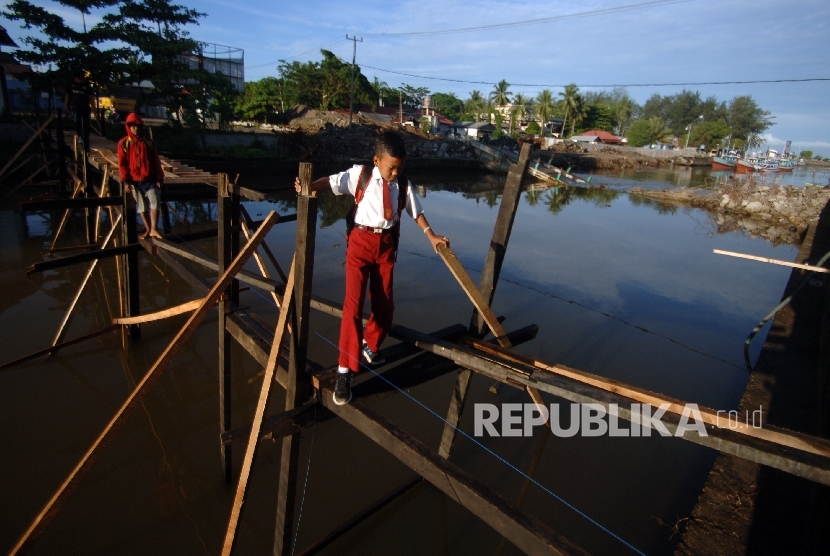Seorang siswa SD melintasi jembatan darurat yang menghubungkan Muara dengan Desa Pauh, Kota Pariaman, Sumatera Barat, Senin (18/4).