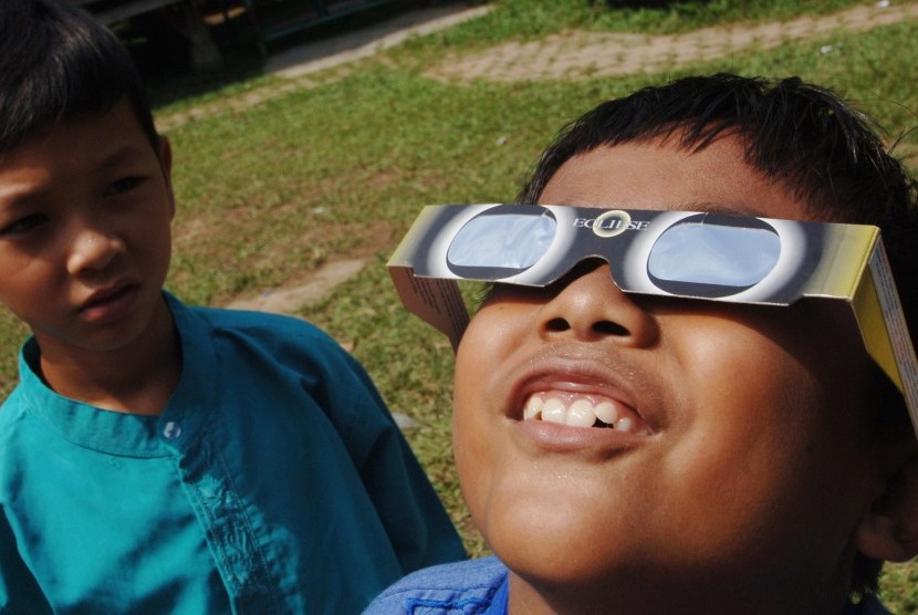 Seorang siswa Sekolah Alam Minangkabau mencoba kacamata khusus untuk pengamatan gerhana matahari yang dibagikan di sekolah mereka, di Padang, Sumatera Barat, Jumat (4/3).