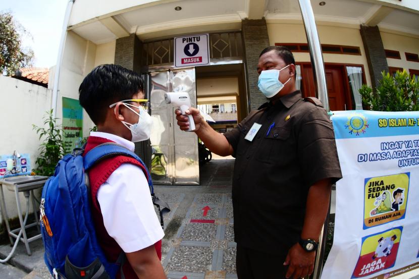 Seorang siswa tengah diukur suhu tubuhnya sebelum mengikuti Pembelajaran Tatap Muka Terbatas (PTMT) di Bandung.