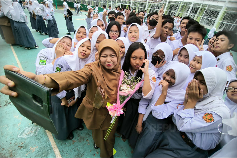 Seorang guru berswafoto bersama siswanya di sela peringatan Hari Guru Nasional di SMA Negeri 12 Bandung, Senin (27/11/2023). Hari Guru Nasional diperingati setiap 25 November setiap tahunnya. Tanggal ini diadopsi dari hari jadi Persatuan Guru Republik Indonesia (PGRI).