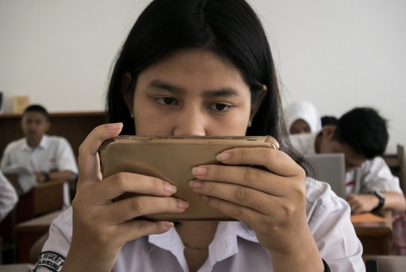 Seorang siswi menggunakan gawai saat mengerjakan soal UASBN 2019 di SMA Negeri 9 Kota Bandung, Jawa Barat, Senin (18/3/2019).